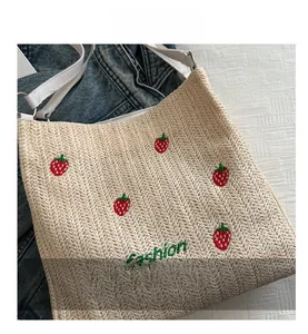 Detail of woven straw tote bag with strawberry embroidery and fashion lettering