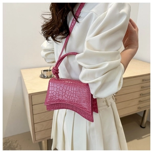 Detail of dark pink crocodile-embossed leather small square bag with curved base