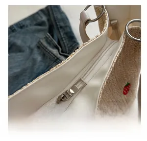 Detailed shot of smooth metal zipper and strawberry embroidery on woven straw tote