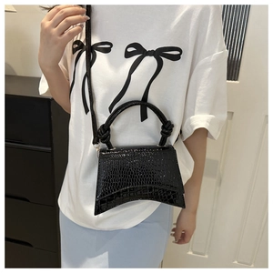 Model wearing a black crocodile pattern hourglass bag with knotted handle and strap
