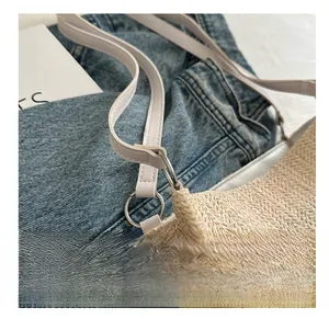 Detail of silver metal ring connecting straw bag body to white faux leather strap
