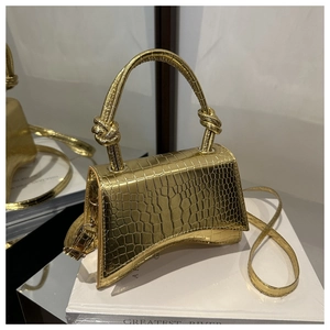 Detail of metallic gold crocodile embossed handbag with curved base and knot handle