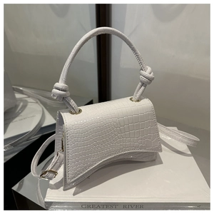 Detail of white crocodile pattern PU leather handbag with curved base and knot handle