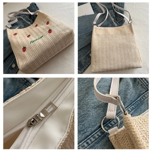 Detail view of woven tote bag with strawberry embroidery and secure zipper closure