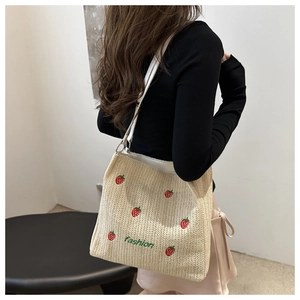 Close-up of woven tote bag with red strawberry embroidery and green fashion text