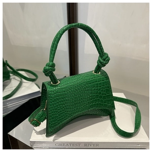 Detail of green crocodile texture handbag with unique curved base and knot handle design