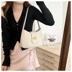 Detail view of cream leather underarm bag with elegant gold buckle on a model