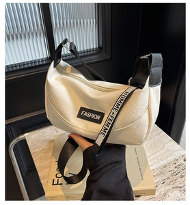 Close-up of white lychee grain leather crossbody bag with logo tag and lettered strap