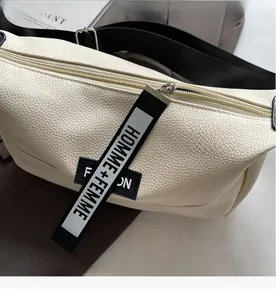 Detail of lychee pattern leather bag with contrast strap and sport style branding