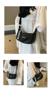 Detail of minimalist black pebbled leather crossbody bag with adjustable wide shoulder strap