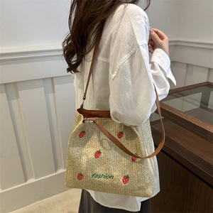 Beige woven strawberry tote bag with brown faux leather straps for summer beach use