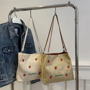 Fashionable straw tote bag with strawberry embroidery and fashion text on metal hanger