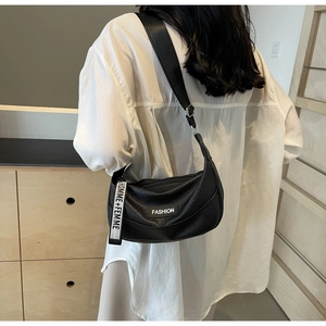 Close-up of black lychee leather crescent bag featuring white HOMME + FEMME ribbon strap