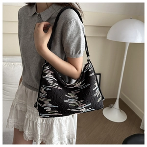 Détail du sac bandoulière matelassé noir avec broderie colorée sur tissu haute densité