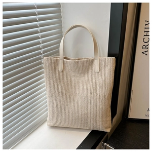 Detailed view of beige woven tote bag featuring textured V-pattern and light cream handles