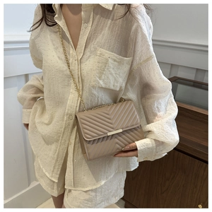 Dettaglio borsa a tracolla trapuntata beige con catena dorata e fibbia rettangolare