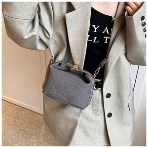 Close-up of grey tweed crossbody bag with gold hardware and adjustable strap on model