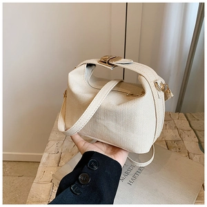 Close-up of beige woven texture pillow bag with gold clasp and adjustable strap