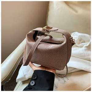 Detail of brown woven dumpling bag with gold buckle and adjustable thin shoulder strap