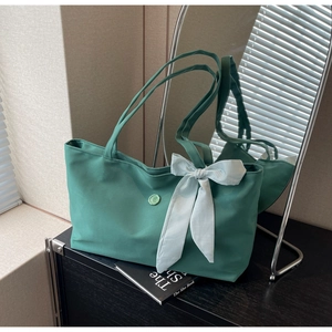 Close-up of light green tote bag featuring a checkered bow and circular brand logo