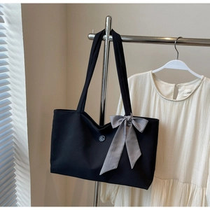 Close-up of black canvas tote bag with a checkered bow ribbon and decorative button