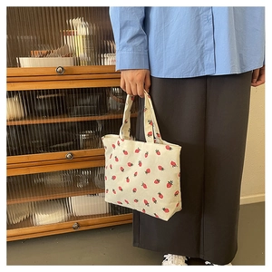 Detailed macro view of cream corduroy tote bag with small red strawberry print patterns