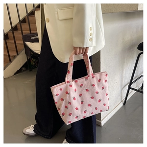 Pink corduroy tote bag with strawberry pattern shown in a soft lifestyle setting