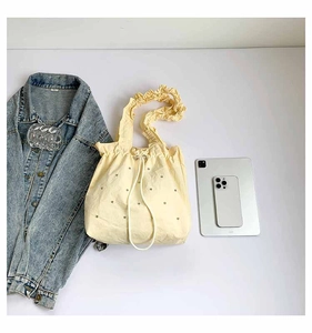 Flat lay of a yellow pleated tote bag with rhinestones, shown with an iPad for size reference