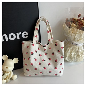 Détail d'un sac cabas en velours côtelé blanc avec broderie fraise et bouton-pression en métal