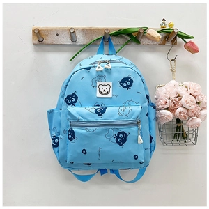 Detail eines hellblauen Kinderrucksacks mit Luck Day Print und Happy Bear Logo-Etikett