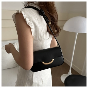 Détail du sac sous l'aisselle en cuir noir avec boucle dorée en croissant sur modèle