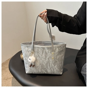 Close-up of silver tote bag with crinkled metallic texture and plush white charm