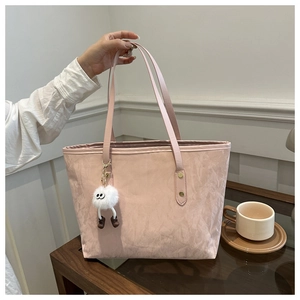 Detail of pink pleated tote bag with plush charm accessory and golden metal hardware