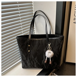 Close-up of black pleated texture tote bag with a cute white plush monster pendant