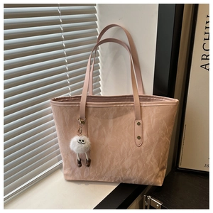 Detailed shot of a pink tote bag with soft texture and a cute white plush keychain charm