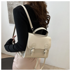 Detail of cream mini faux leather backpack with double buckle straps on female model