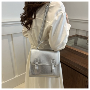 Close-up of metallic silver mini backpack with vintage buckle detail on a model