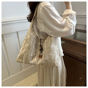 Détail du cabas beige avec texture plissée et motifs de feuilles de bambou blancs