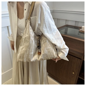 Détail du sac fourre-tout plissé doré avec des motifs élégants de feuilles de bambou