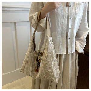 Détail de la texture plissée du sac en toile avec perles décoratives en bois