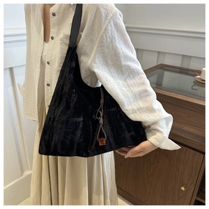 Détail du sac cabas en velours noir avec cordon tressé et pendentif ambre