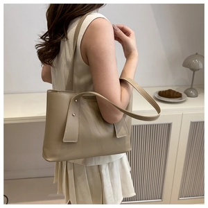 Minimalistische beige Shopper-Tasche aus Leder mit Nieten am Model für den Alltag