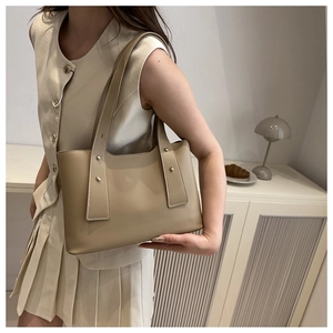 Detail der beigen Leder-Tragetasche mit Goldnieten in minimalistischem Ambiente
