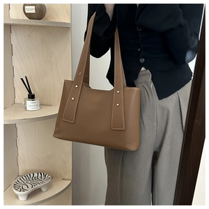 Braune matte Leder-Einkaufstasche mit breitem Gurt und Goldnieten in Lifestyle-Szene