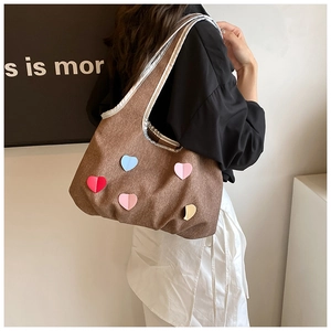 Close-up of brown canvas shoulder bag featuring five colorful leather heart patches