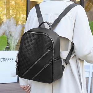 Detail of woman wearing a black checkered backpack with faux leather and silver zippers