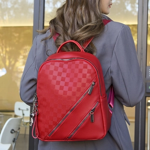 Detail of red checkered backpack with astronaut charm and twin diagonal zip pockets