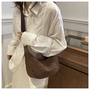 Brown corduroy shoulder bag with strawberry embroidery and dark strap on model