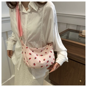 Detail of pink corduroy crossbody bag with red strawberry embroidery and nylon strap