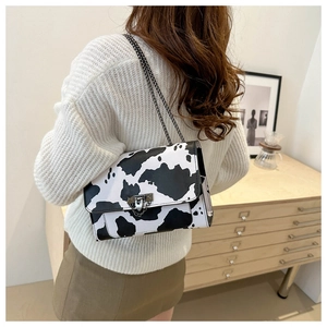 Detail of cow print crossbody bag with silver metal chain and buckle on leather flap